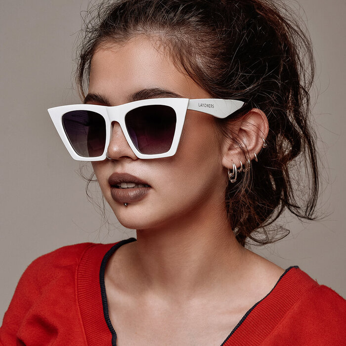 model in red top and hair up with lip piercing showcasing large white modern sunglasses 