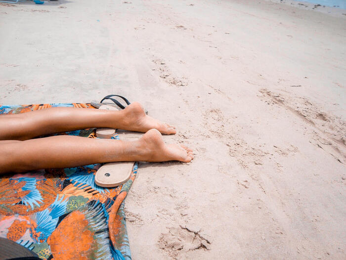 two legs on the beach on a colorful towel sun bathing