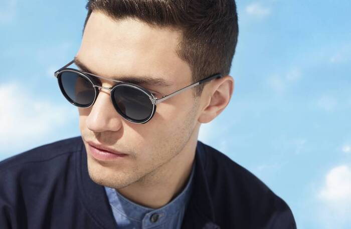 pick eyeware a man model dressed in dark blue with dark hair showcasing a pair of dark sunglasses