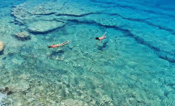 two people swimming and snorkeling in clear blue waters 