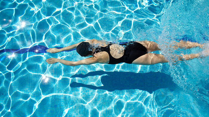 swimming summer sports woman in the water photographed from above in her black swimsuit 