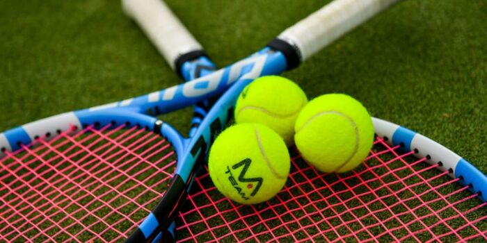 tennis balls and two rackets lying on the tennis ground