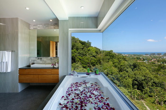 villa beyond phuket thailand bathroom with a view bathtub filled with rose petals next to a large window overlooking green landscape