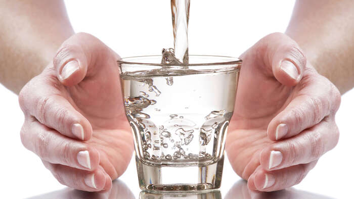 mineral water pouring in a glass with two hands surrounding it 