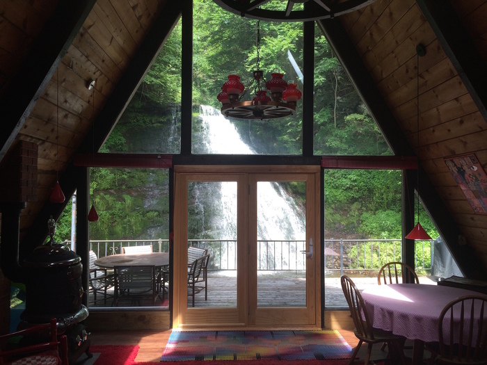 large windows overlooking a waterfall hut wooden house 