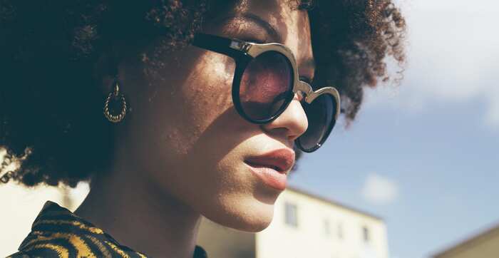 woman with afro hair golden earrings and fancy branded sunglasses close up