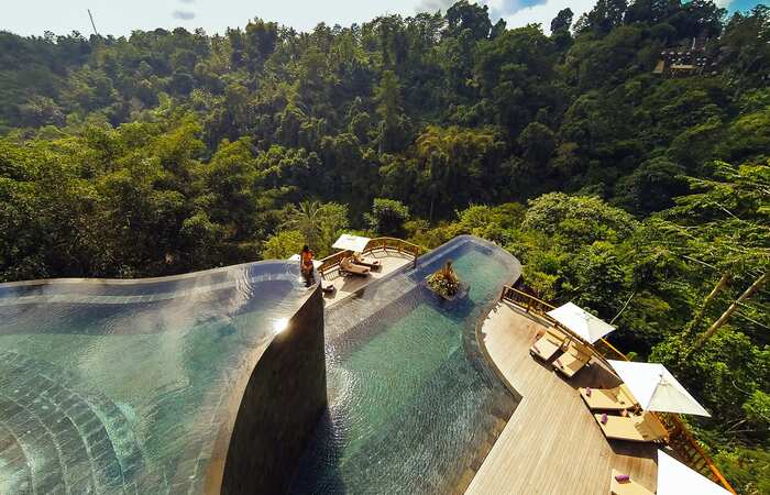 bali indonesia infinity pool overlooking the jungle with wooden decking and lounge chairs