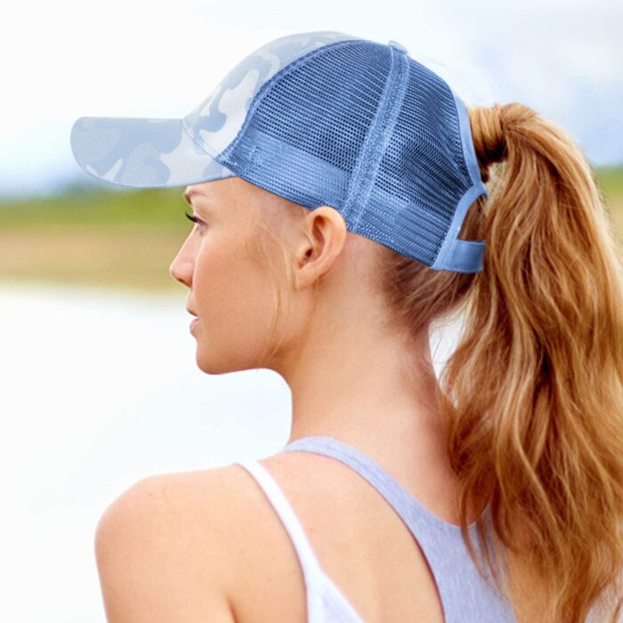 woman with her back to the camera wearing a light blue baseball cap with her blond hair in a ponytail 