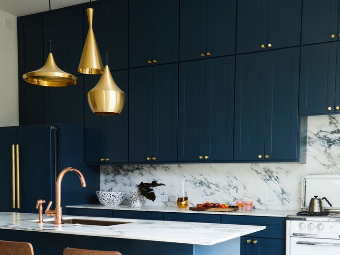 dark blue kitchen with metal lights and marble countertops