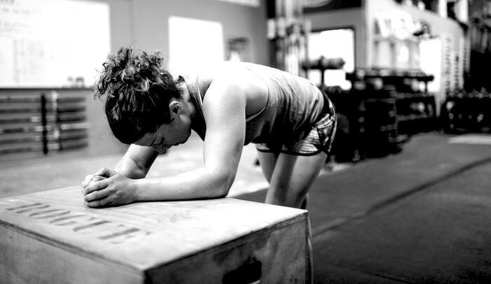 black and white photograph of a woman with her hair up in the fitness overtraining and looking tired