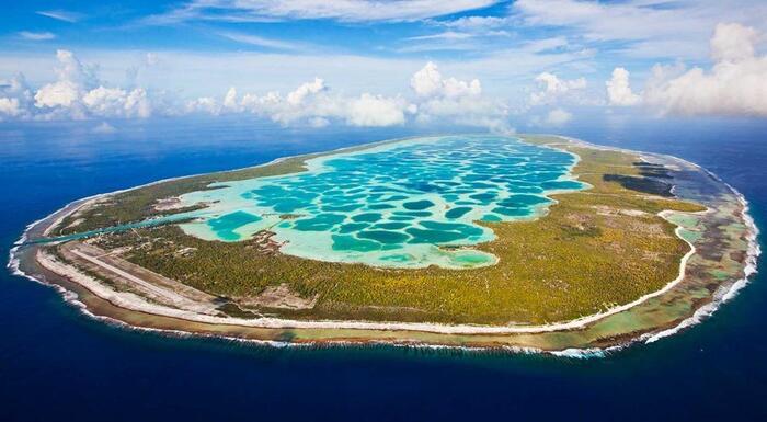 french polynesia beautiful island with bright blue water in the middle and a green ring around it