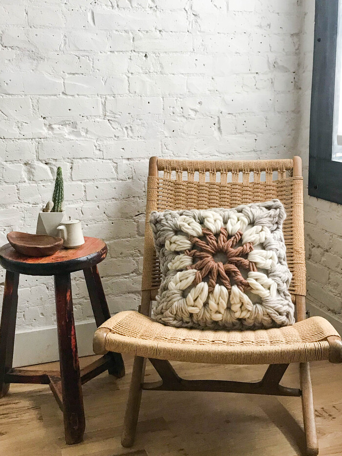 granny pillow on a rocking woven chair in a white room with a wooden floor