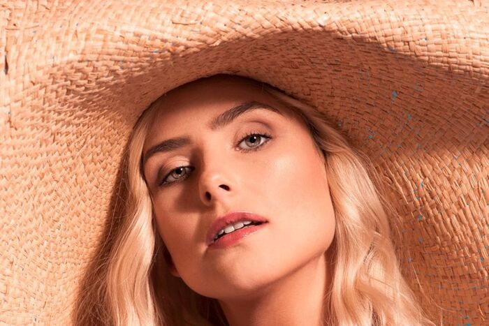 make up tips sunkissed skin blond woman with a large wide brim hat and light eyes looking into the camera