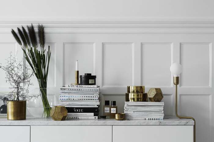 metal interior decor brass and bronze home decor accessories on a white piece of furniture against a white wall