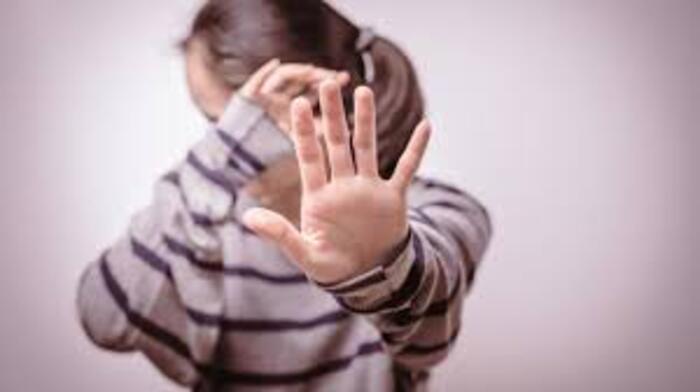 narcissistic abuse woman in a striped shirt hiding her face and stretching her hand to protect herself