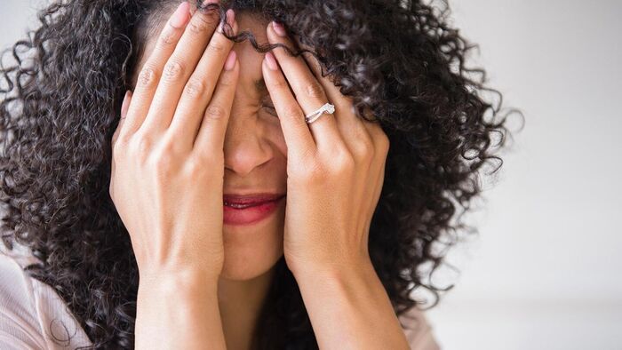 panic attack woman with curly dark hair holding her hands in front of her face