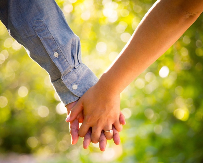 relationship couple holding hands man in a blue shirt and a girl with an engagement ring