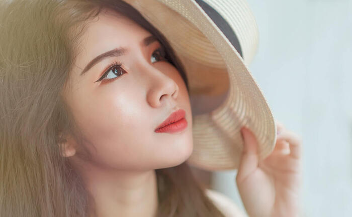 sun and skin asian girl with a sunhat on looking up with light make up