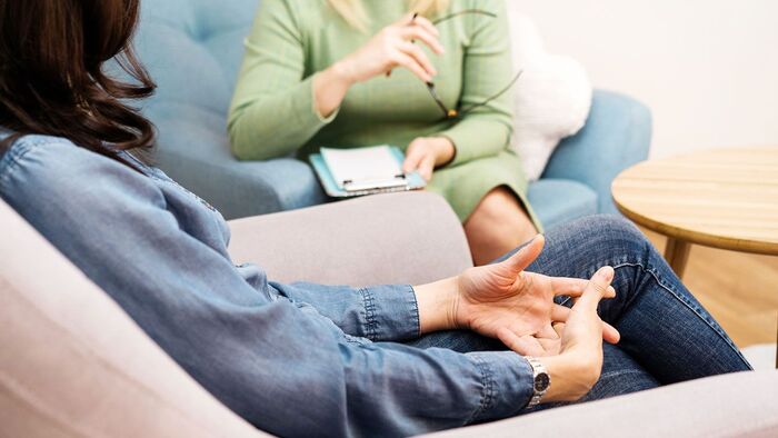 two women in therapy sitting in chair and speaking 