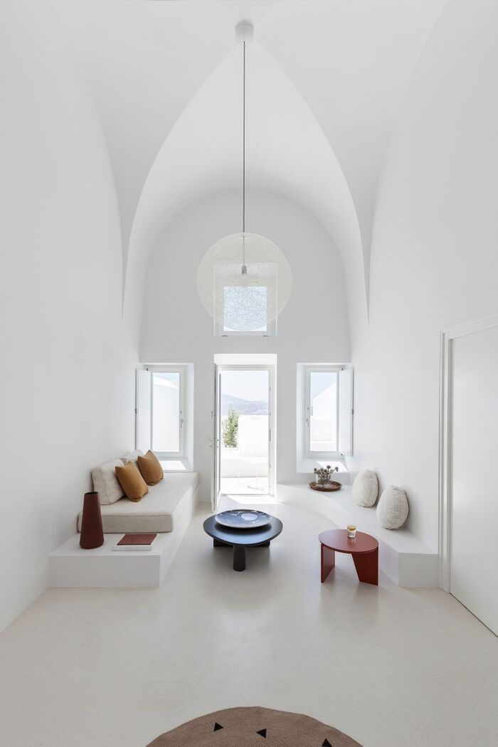 white cave with high ceilings and minimal furniture with colorful accent tables