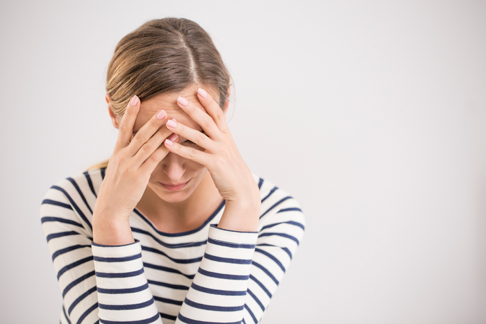 woman anxiety woman in striped shirt looking down and holding her head