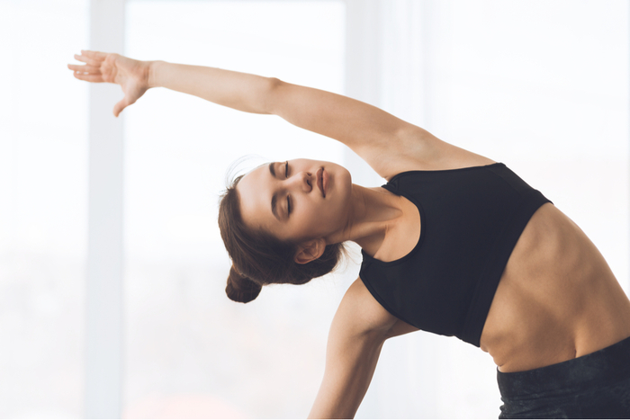 woman dressed in black doing yoga posture with her hair up in a bun