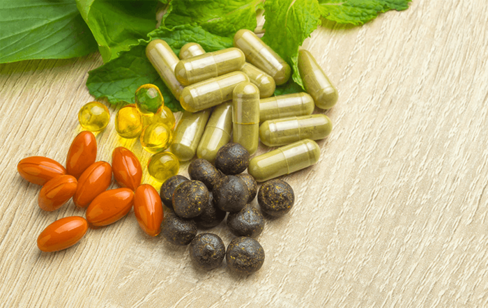 antioxidants capsules and pills of different shape and size on a table surface with some green leaves