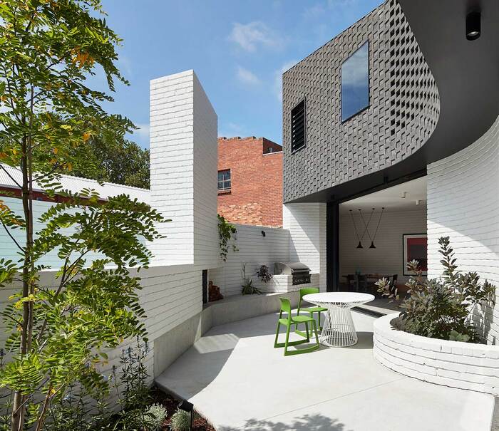 modern architecture curved black and white house with a white yard and living plants