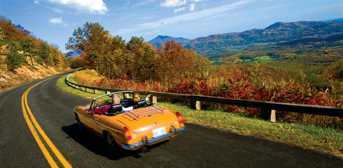 blue ridge parkway couple driving in a classic cabrio orange car on a scenic road watching the nature around