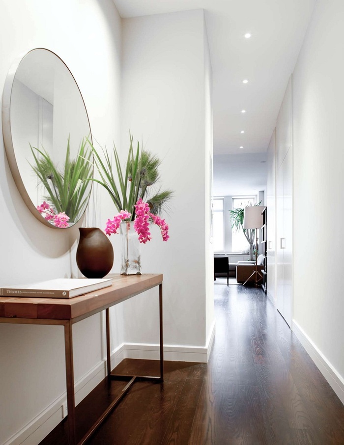clean lines white hallway with a dark wooden floor large round mirror and some decorations