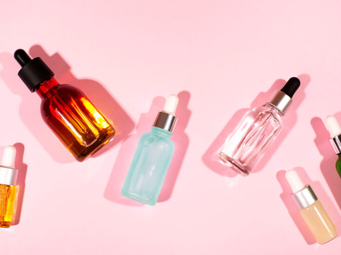 different serums in bottles on a light pink background