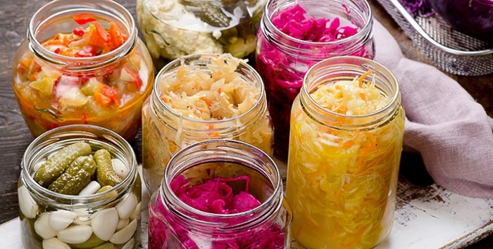 fermentation jars with fermented veggies cabbage cucumbers and more on a wooden table
