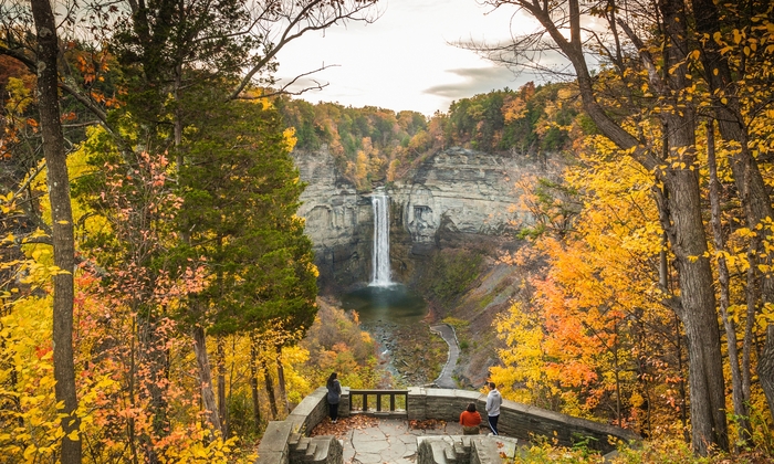 beautiful nature in fall people standing on a stone terrace overlooking at a waterfall surrounded by rocks and colorful trees