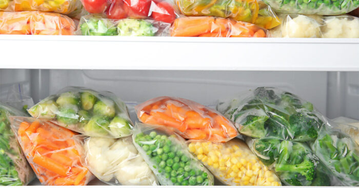 food freezing bags of frozen vegtables stacked in a fridge