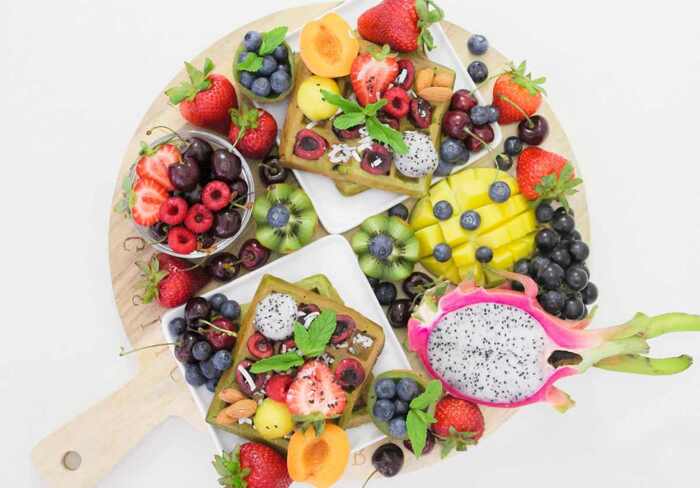 a round platter with different fruits and vegetables tropical fruits on a white background