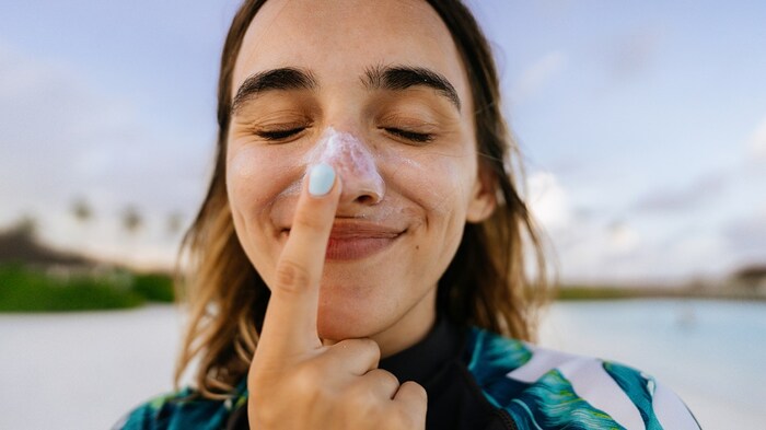 girl face close up applying sunscreen on her nose with her eyes closed smiling 