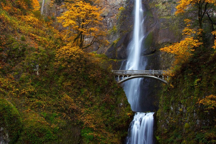 Gorge with a waterfall and bridge with yellow foliage and rocky slopes