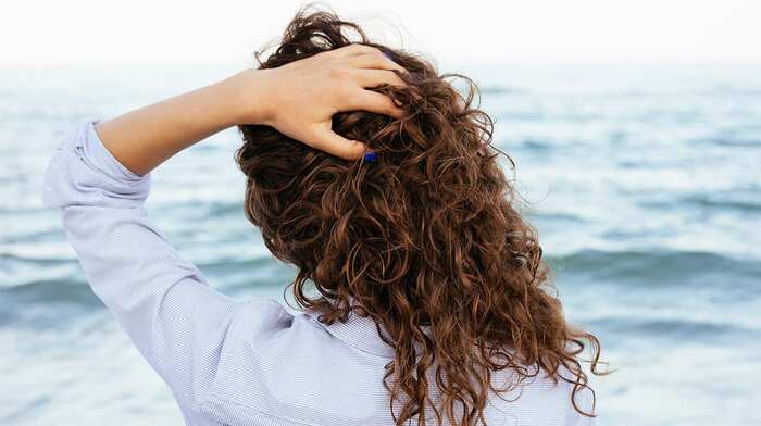 hair in the sun woman looking at the sea and touching her hair back shot 