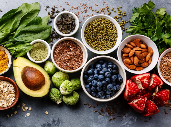 healthy diet antioxidant foods different nuts and vegetables and fruits on a dark blue surface in white bowls