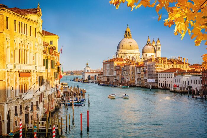 italy fall venice sunlit canal with duomo in the background and yellow leaves in the forefront