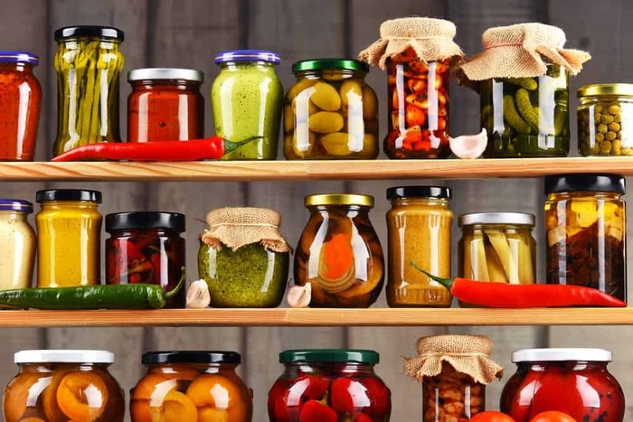 jarring method shelves with different jars arranged with some peppers and garlic for decoration