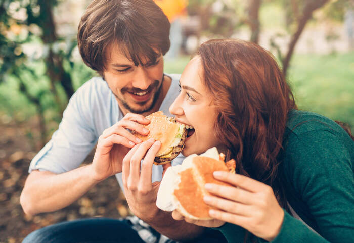 metabolic changes during the year couple eating sandwich together smiling and looking at each other