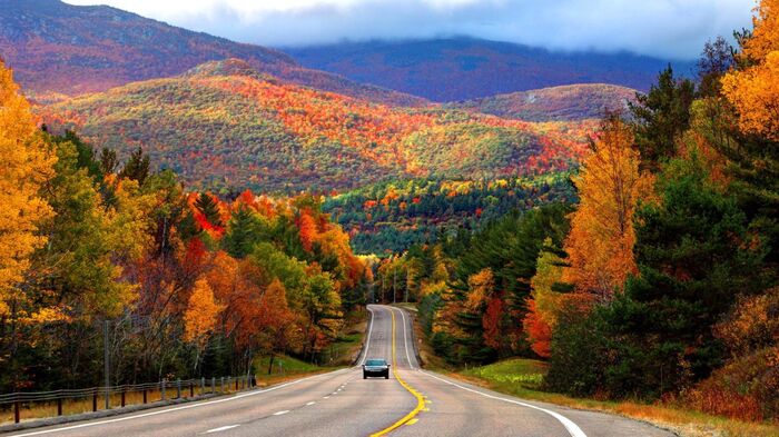 new york area drive in fall mountain landscape and a road with a car on it surrounded by colorful trees