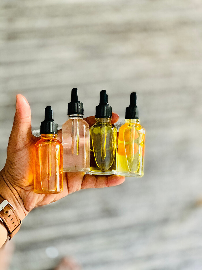 a male hand holding four different bottles of face serums on a grey background