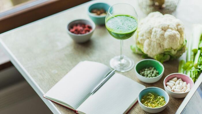 meals for strong immune system green vegetables smoothie and a notebook with a pen and some notes