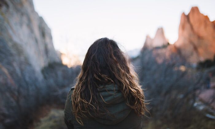 sustainable tourism woman with blond wavy hair with her back to the camera overlooking a mountainous landscape