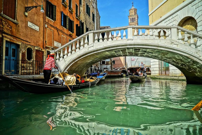 a channel in Venice with a bridge and a gondola passing by