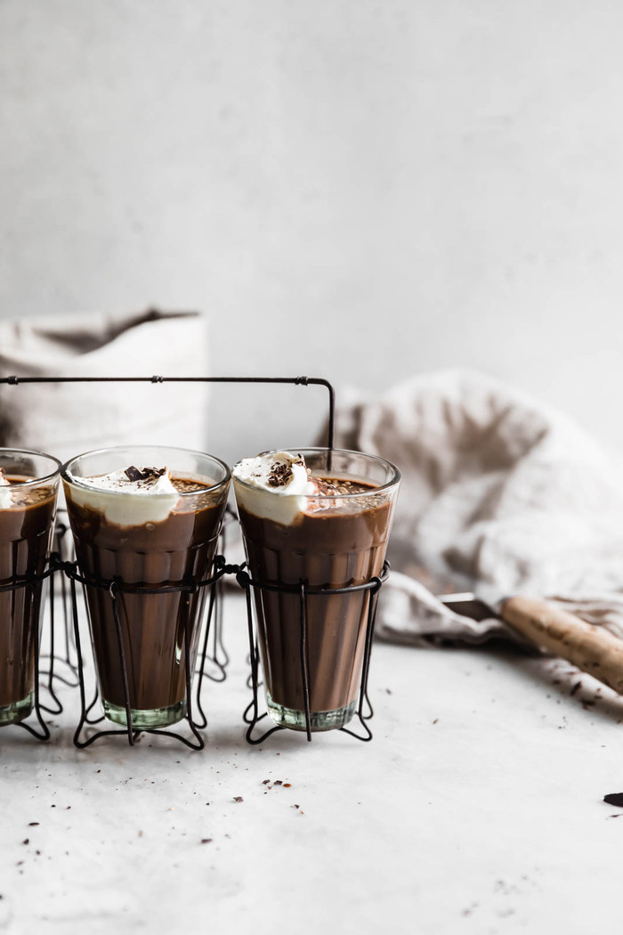 Tahini hot chocolate with some cream on top in tall glasses ready for serving
