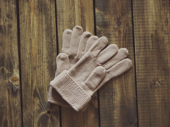 get warm with a pair of beige gloves on a wooden table