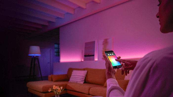 ambient light bulbs woman holding her phone tuning the pink lighting at home
